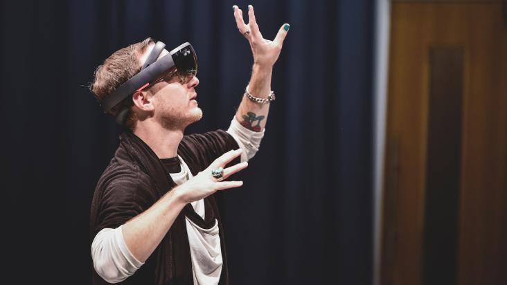 A white man wearing a VR headset with hands in the air.